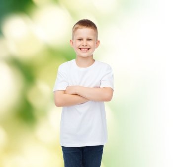 advertising, ecology, people and childhood concept - smiling little boy in white blank t-shirt over green background