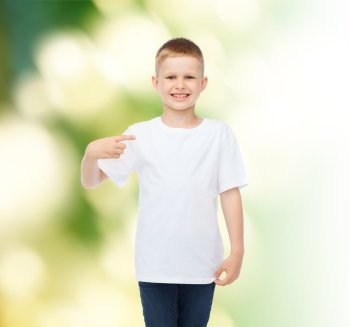 advertising, ecology, gesture and childhood concept - smiling boy in white blank t-shirt pointing finger at himself over green background
