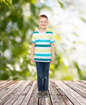 happiness, childhood, summer and people concept - smiling little boy in casual clothes over plants and wooden floor background