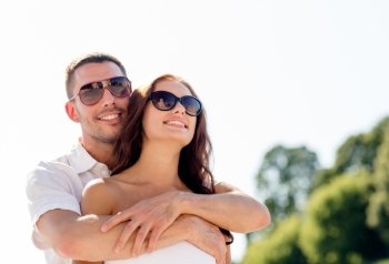 love, wedding, summer, dating and people concept - smiling couple wearing sunglasses hugging in park