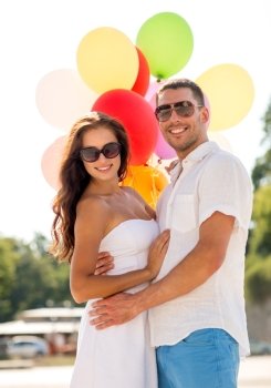 love, wedding, summer, dating and people concept - smiling couple wearing sunglasses with balloons hugging in park