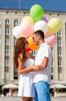 love, wedding, summer, dating and people concept - smiling couple wearing sunglasses with balloons hugging in city