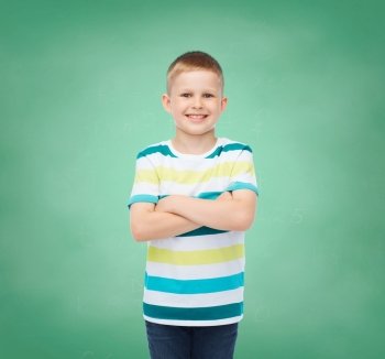 happiness, childhood, school, education and people concept - smiling little boy in casual clothes over green board background