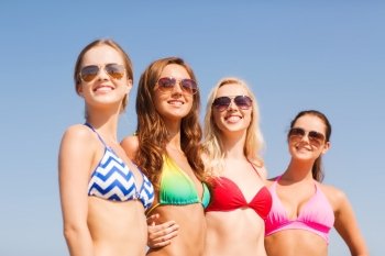 summer vacation, holidays, travel and people concept- group of smiling young women on beach over blue sky background