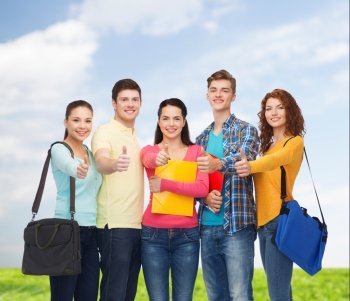 friendship, summer vacation, education and people concept - group of smiling teenagers with folders and school bags showing thumbs up