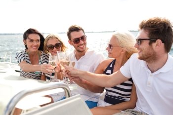vacation, travel, sea, friendship and people concept - smiling friends with glasses of champagne on yacht