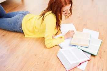 leisure, education and home concept - smiling teenage girl reading books on floor