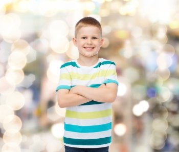 happiness, childhood, holidays and people concept - smiling little boy in casual clothes with crossed arms over sparkling background