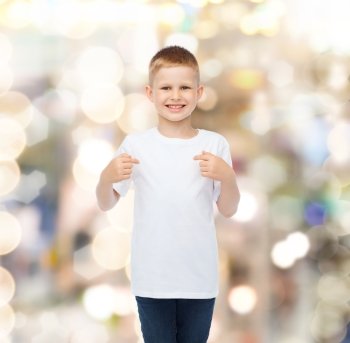 advertising, gesture, people and childhood concept - smiling boy in white blank t-shirt pointing fingers himself over holidays background