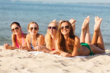 summer vacation, holidays, travel and people concept - group of smiling young women in sunglasses lying on beach