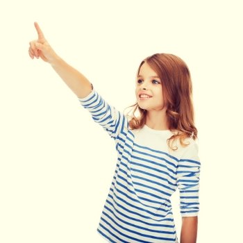 education, school and virtual screen concept - cute little girl pointing in the air or virtual screen