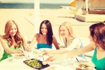 summer holidays and vacation concept - smiling girls in cafe on the beach