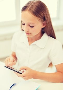 education, school, technology and internet concept - little student girl with notebook and smartphone at school