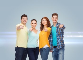 friendship, dream, future and people concept - group of smiling teenagers pointing fingers on you over gray background with laser light