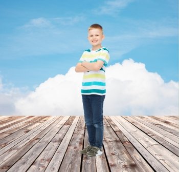 happiness, childhood, summer and people concept - smiling little boy in casual clothes over blue sky and wooden floor background