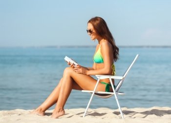 summer vacation, holidays and people concept - smiling young woman sunbathing in lounge on beach