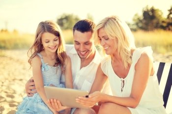 summer holidays, family, child and technology concept - smiling family at beach with tablet pc computer