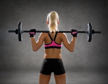 fitness, sport and dieting concept - sporty woman exercising with barbell from back over concrete wall background