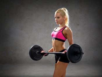 fitness, sport and dieting concept - sporty woman exercising with barbell over concrete wall background