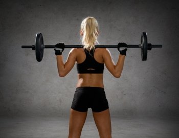 fitness, sport and dieting concept - sporty woman exercising with barbell from back over concrete wall background