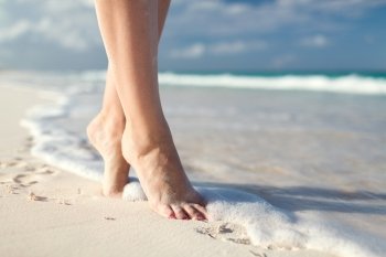 summer, beach, leisure and body part concept - closeup of woman legs on sea shore