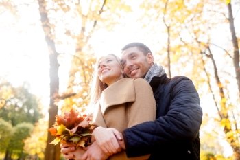 love, relationship, family and people concept - smiling couple with bunch of leaves hugging in autumn park