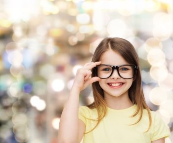 education, school and vision concept - smiling cute little girl in black eyeglasses