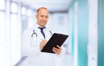 medicine, profession and healthcare concept - smiling male doctor with clipboard and stethoscope writing prescription over hospital background