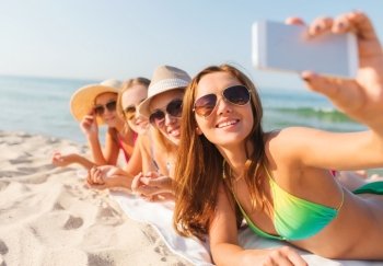 summer vacation, travel, technology and people concept - group of smiling women in sunglasses making selfie with smartphone on beach