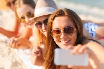 summer vacation, travel, technology and people concept - close up of smiling women in sunglasses and hats making selfie with smartphone on beach