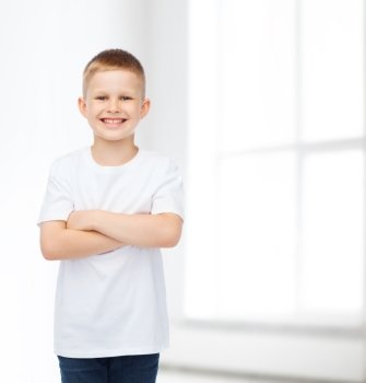 advertising, people, home, school and childhood concept - smiling little boy in white blank t-shirt over white room background