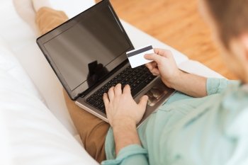 technology, leisure, shopping, banking and lifestyle concept - close up of man with laptop computer and credit card at home