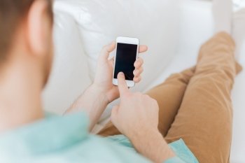 communication, business, home and technology concept - close up of man with smartphone texting message sitting on couch at home