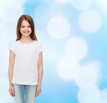 advertising, childhood and people - smiling little girl in white blank t-shirt over blue background