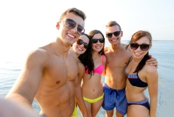 friendship, leisure, summer, technology and people concept - group of smiling friends making selfie on beach