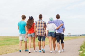 holidays, vacation, love and friendship concept - group of teenagers walking outdoors from back