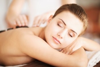 beauty concept - woman in spa salon with hot stones