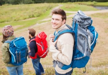 adventure, travel, tourism, hike and people concept - group of smiling friends with backpacks outdoors