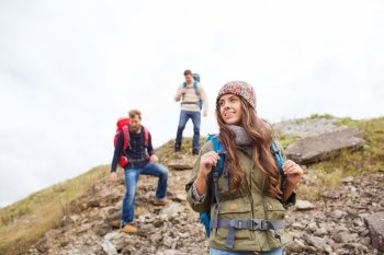 adventure, travel, tourism, hike and people concept - group of smiling friends with backpacks walking down downhill