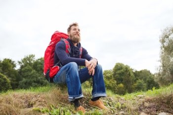 adventure, travel, tourism, hike and people concept - smiling man with red backpack sitting on ground