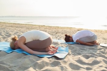 fitness, sport, people and lifestyle concept - couple making yoga exercises on mats outdoors