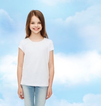 advertising, dream, childhood and people - smiling little girl in white blank t-shirt over cloudy sky background