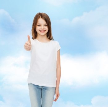 advertising, dream, childhood, gesture and people - smiling little girl in white blank t-shirt showing thumbs up over cloudy sky background