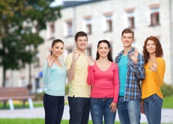 friendship, education, summer vacation and people concept - group of smiling teenagers showing ok sign over campus background