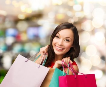 sale, gifts, christmas, xmas concept - smiling woman in red dress with shopping bags