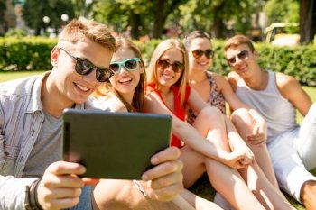 friendship, leisure, summer, technology and people concept - group of smiling friends with tablet pc computer making selfie in park