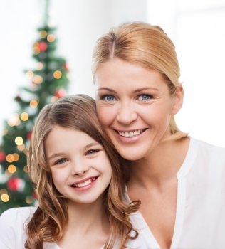 family, childhood, holidays and people - smiling mother and little girl over christmas tree background
