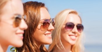 summer vacation, holidays, friendship and people concept - close up of smiling young women in sunglasses