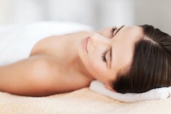 beauty and spa concept - beautiful woman in spa salon lying on the massage desk