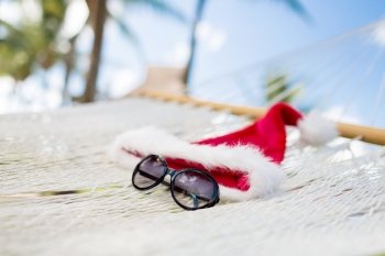 vacation, christmas and holiday concept - picture of hammock with santa helper hat and sunglasses
